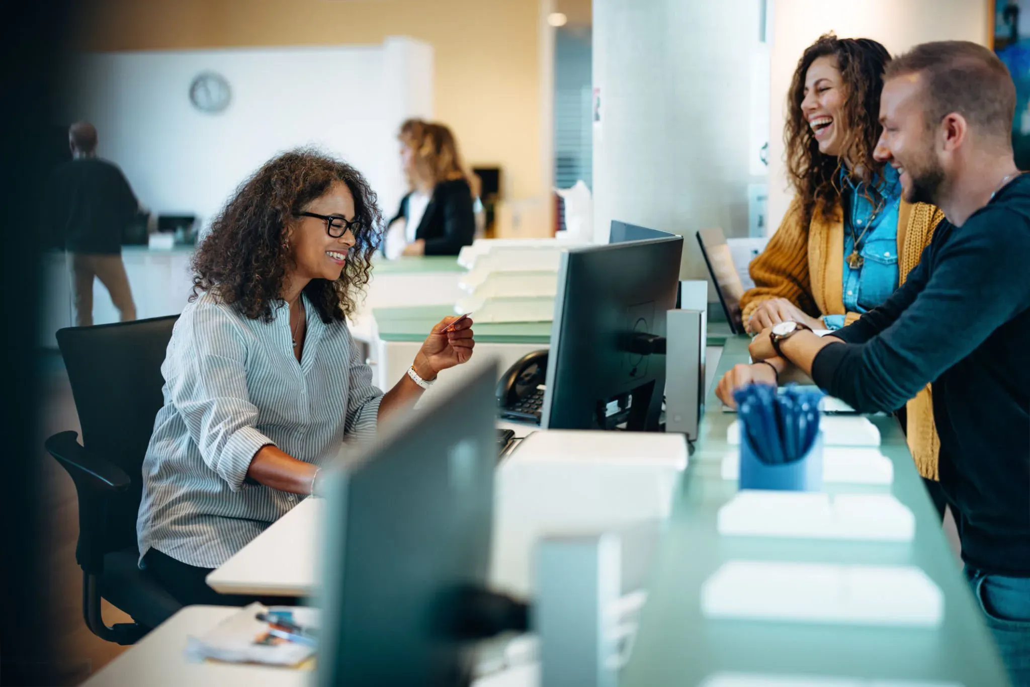 An agency staff member helping two residents at a public service front desk